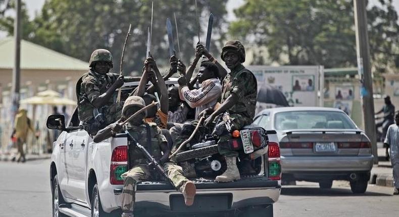 Soldiers and people carrying machetes ride on the back of a vehicle along a street in Gombe , Nigeria, January 30, 2015. 