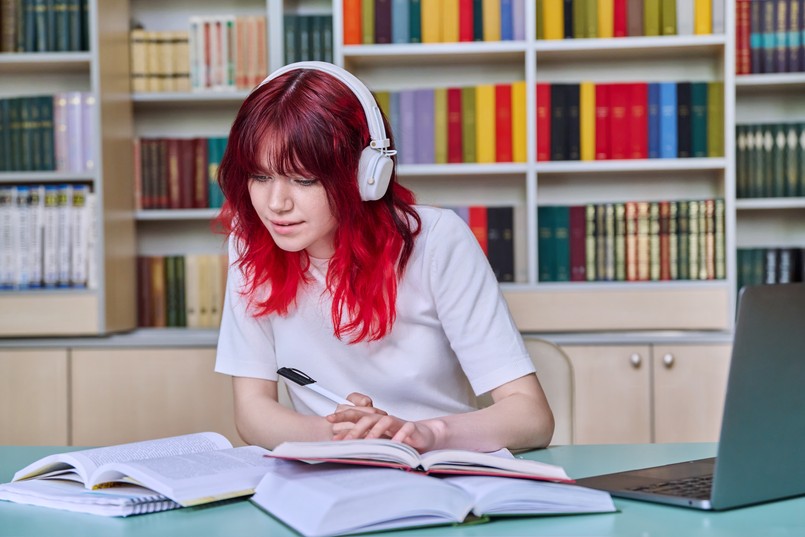 młoda kobieta, studentka, uczennica czyta, uczy się, biblioteka