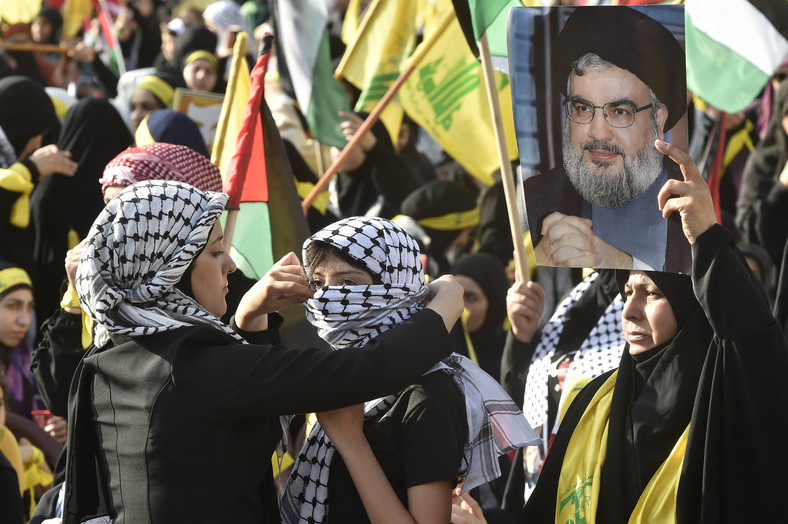 Zwolenniczka Hezbollahu poprawia palestyńską chustę swojej przyjaciółce podczas przemówienia przywódcy Hezbollahu Hassana Nasrallaha na ekranie na południowych przedmieściach Bejrutu