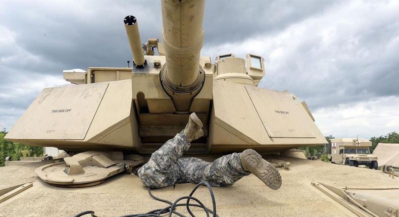 A US soldier scrambles into the driver's compartment of an M1A1 Abrams tank at Fort Benning in Georgia in May 2016.Army photo by Sgt. 1st Class Jon Soucy