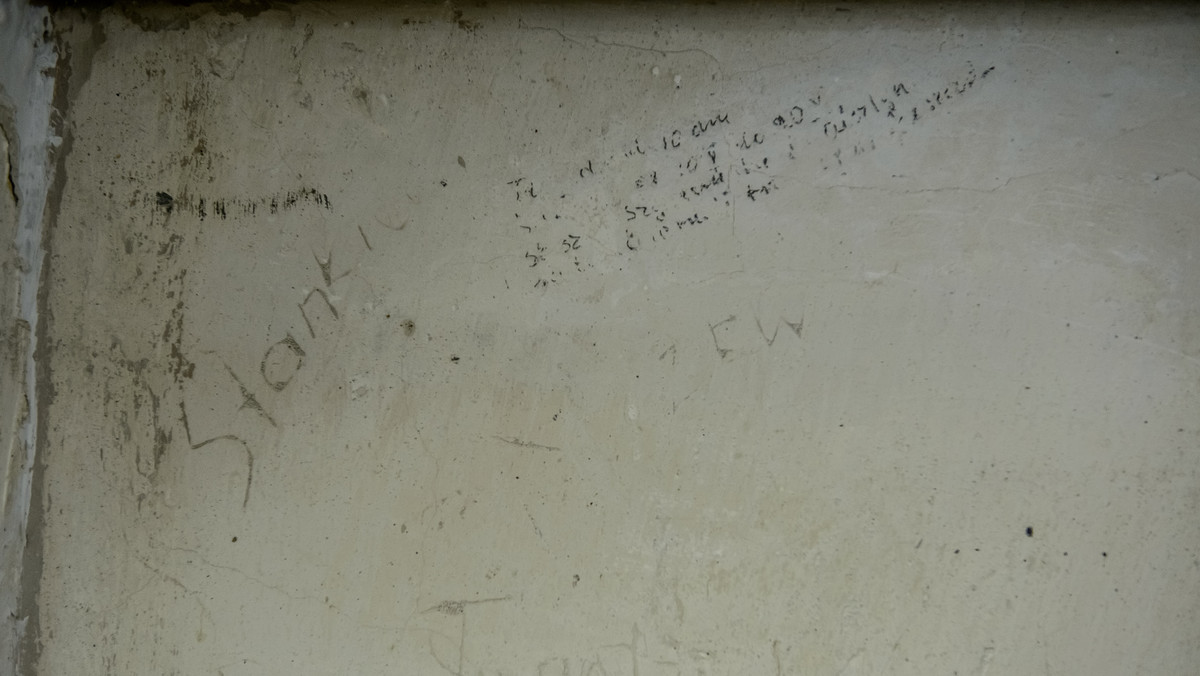 Napisy, daty i modlitwy na ścianach dawnego aresztu w Muzeum pod Zegarem w Lublinie