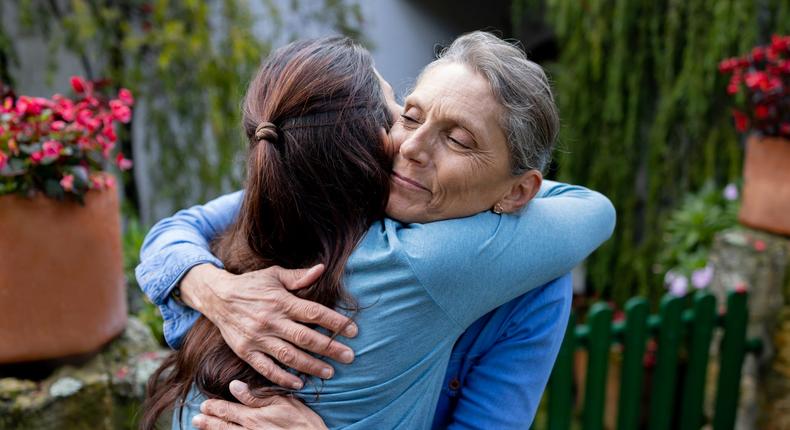 A mother embraces her daughter infront of their home.Hispanolistic/Getty Images