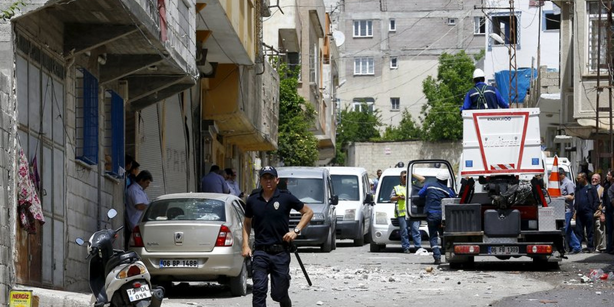 A riot police officer runs away from the site after two rockets hit the Turkish town of Kilis