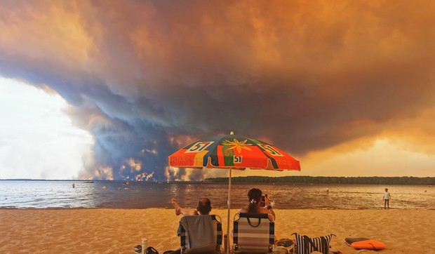 Posetioci plaže odmaraju se na plaži Mučik na obali jezera Lakano u Lakanou, na jugozapadu Francuske, dok požar besni u Žirondi, 24. jul 2026.