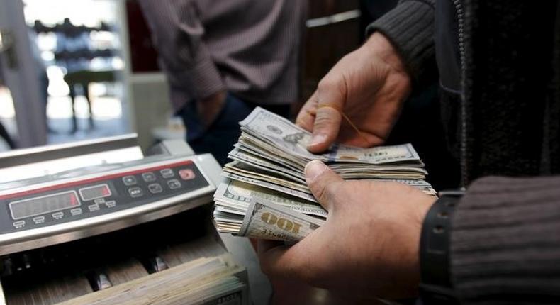 A man counts wads of U.S. dollars on a money counting machine at a currency exchange shop in Baghdad December 21, 2015. REUTERS/Khalid al Mousily