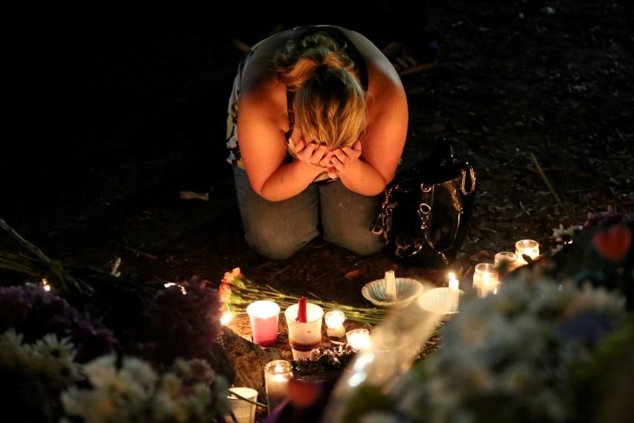 A woman mourns as she sits on the ground and takes part in a vigil for the Pulse night club victims following last week's shooting in Orlando