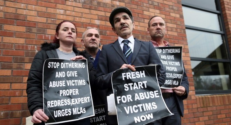 Alleged victims of historical institutional abuse pose outside the Crowne Plaza hotel in Belfast on January 20, 2017 as they arrive to attend the public statement on the publication of the Historical Institutional Abuse Inquiry Report