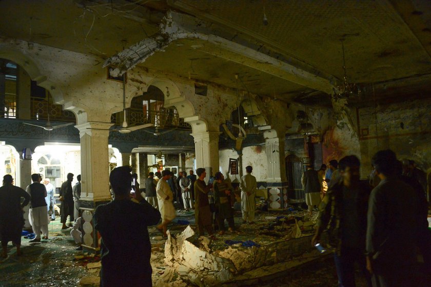 Afghan policemen and relatives inspect at the site of a suicide attack in Herat, Afghanistan