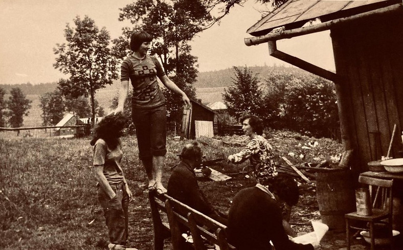 Na zdjęciu: mama Marty stojąca na ławce i zwrócona w jej stronę babcia Celina. Wokół kuzynostwo mamy, w tle Marzeniówka