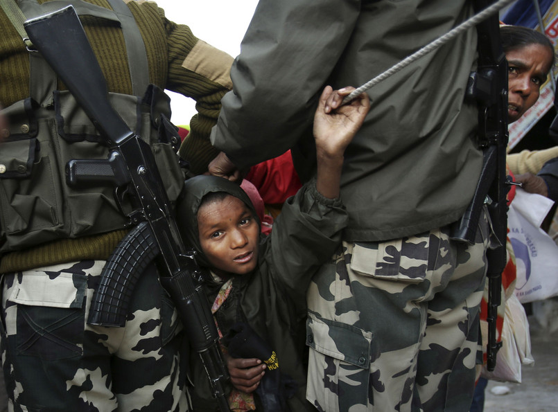Chłopiec przepycha się przez uzbrojonych policjantów strzegących porządku przed jaskinią Amarnath