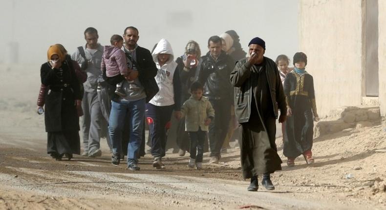 Iraqis walk as they flee their neighbourhoods to safer locations on November 28, 2016 in an eastern district of the city of Mosul during the ongoing figthing between Islamic State group jihadists and government forces