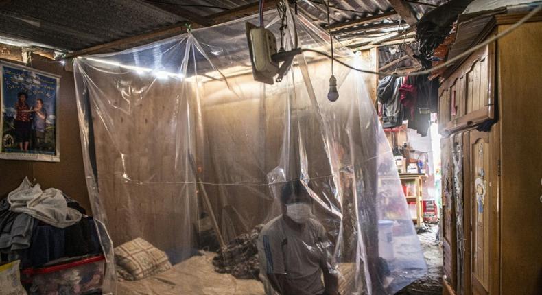 Jonathan, 30, sits on his bed behind a plastic protection as doctors make a round of visits in Ate, on the eastern outskirts of Lima