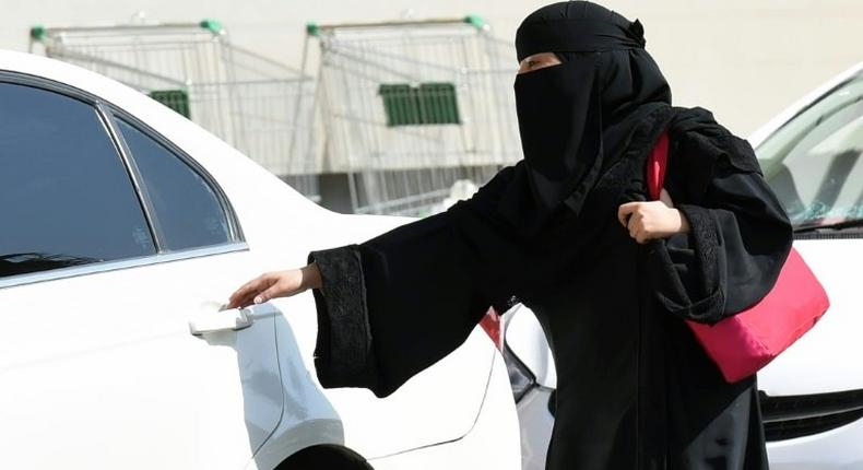 A Saudi woman gets into a taxi at a mall in Riyadh