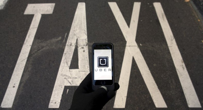 The logo of car-sharing service app Uber on a smartphone over a reserved lane for taxis in a street is seen in this December 10, 2014 file photo illustration. REUTERS/Sergio Perez/Illustration/Files