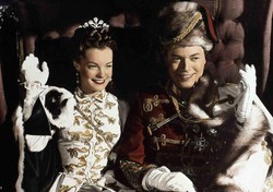 A jelenet a Sissi – Sorsdöntő évek (1957) című filmből látható, és Sissi és Ferenc József magyarországi koronázását idézi meg. A rendező, Ernst Marischka különösen nagy figyelmet fordított arra, hogy a díszletek és kosztümök hitelesen tükrözzék az 1867-es eseményt, amely az Osztrák–Magyar Monarchia megalakulásának egyik kulcsmozzanata volt. Romy Schneider ruháját a valódi Erzsébet királyné koronázási portréi alapján készítették, és külön hangsúlyt fektettek a gyöngyökre, brokátokra, valamint a prémes elemekre.