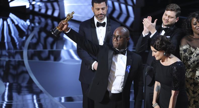Writer and Director Barry Jenkins of Moonlight holds up the best-picture Oscar in front of host Jimmy Kimmel as he stands with producer Adele Romanski.