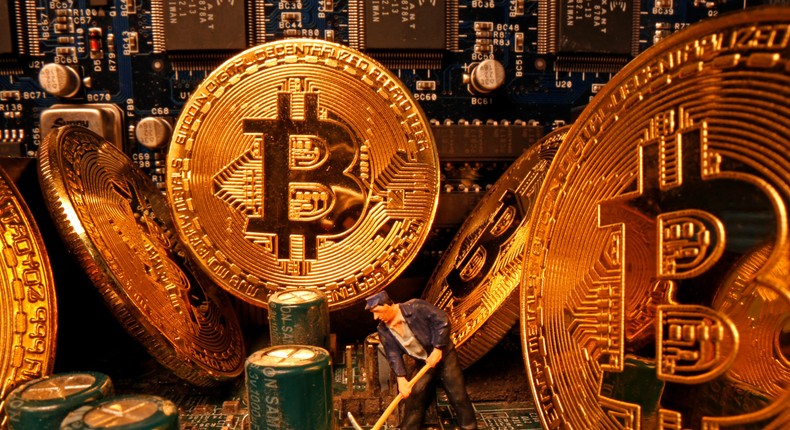 A small toy figure and representations of the virtual currency Bitcoin stand on a motherboard in this picture illustration