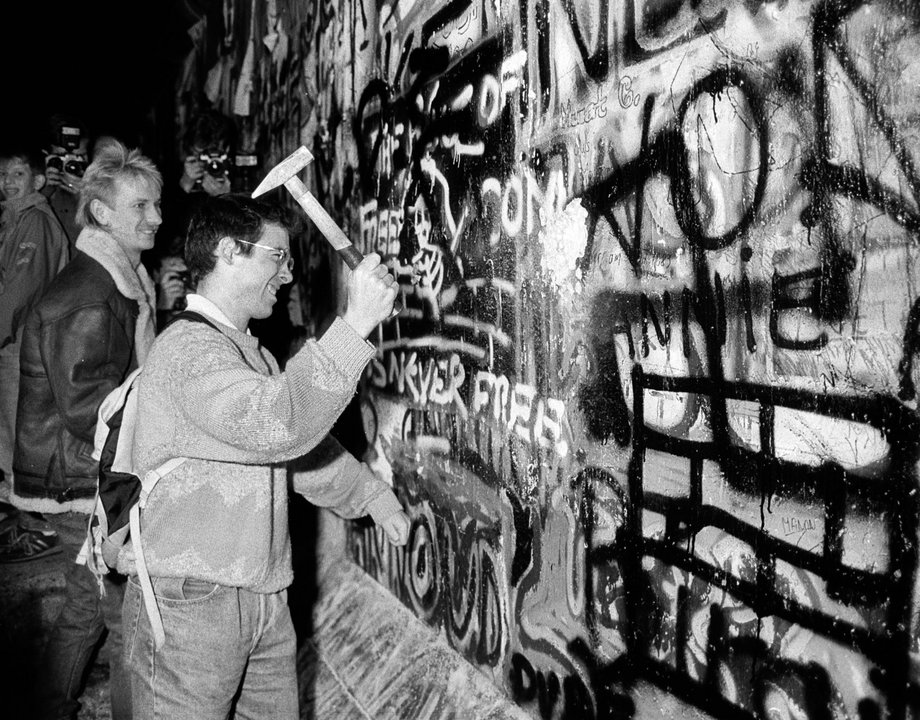 A man hammering a section of the Berlin Wall near the Brandenburg Gate after the opening of the East German border.