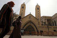 Women pass by the Coptic church that was bombed on Sunday in Tanta