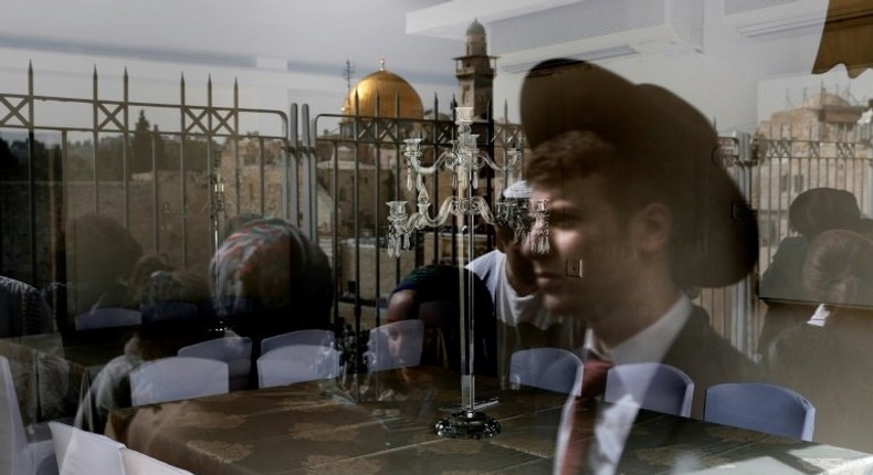 A picture taken through the window of a restaurant shows a reflection of Jews taking part in the Passover priestly blessing at Jerusalem's Western Wall on April 13, 2017, with the Dome of the Rock seen in the background