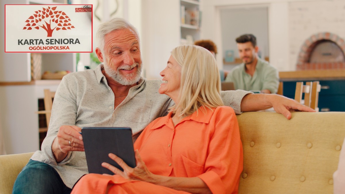 Zadowoleni seniorzy siedzą na kanapie i przeglądają na tablecie zniżki, które można uzyskać z kartą seniora