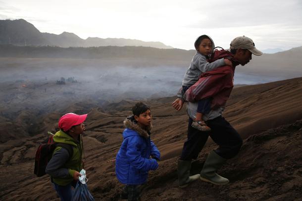 A Hindu villager carries his child up Mount Bromo to attend the Kasada ceremony in Probolinggo