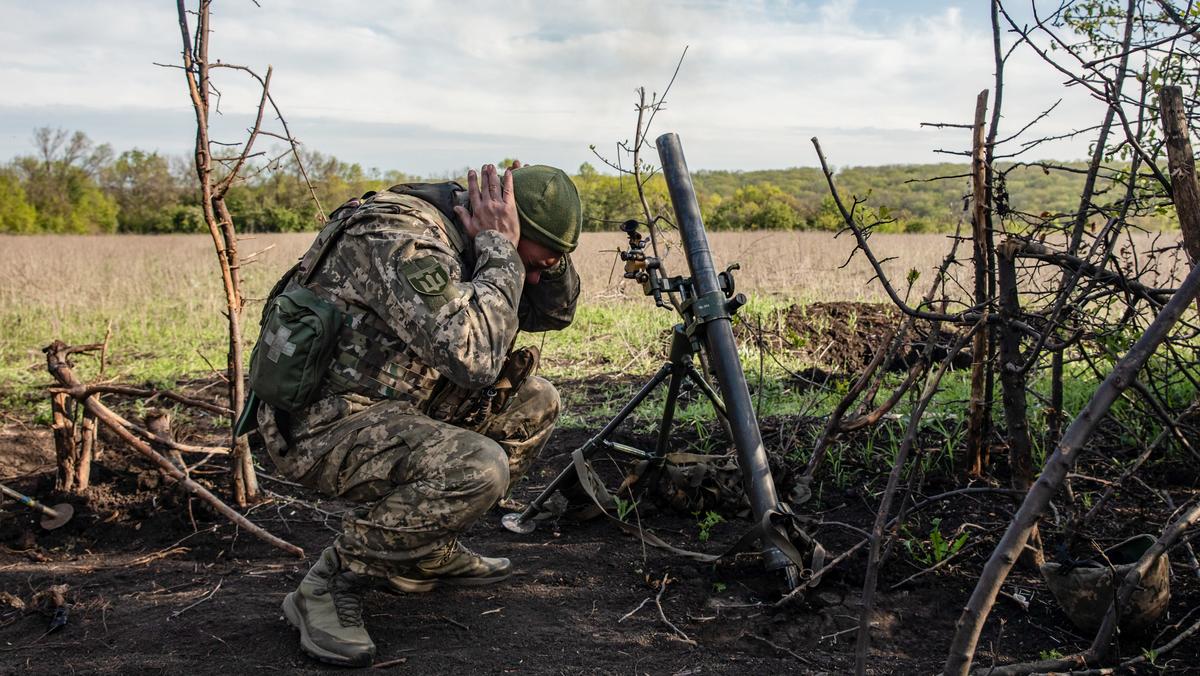 Przedmieścia Bachmutu. Ukraiński żołnierz zakrywa uszy podczas wystrzału moździerza w kierunku pozycji wroga.