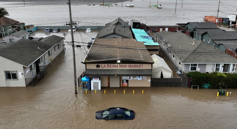 This aerial photograph shows a car and market shop in floodwaters in Pajaro, California on Saturday, March 11, 2023. - Residents were forced to evacuate in the middle of the night after an atmospheric river surge broke the the Pajaro Levee and sent flood waters flowing into the community.JOSH EDELSON/AFP via Getty Images