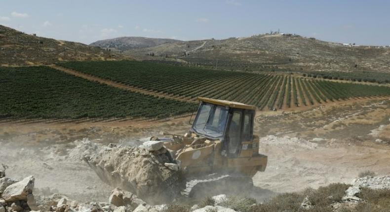 A worker uses a bulldozer to clear the land for the new Amichai settlement, between Ramallah and Nablus in the West Bank, on June 20, 2017