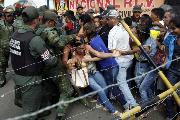 People clash with Venezuelan National Guards as they try to cross the border to Colombia over the Fr