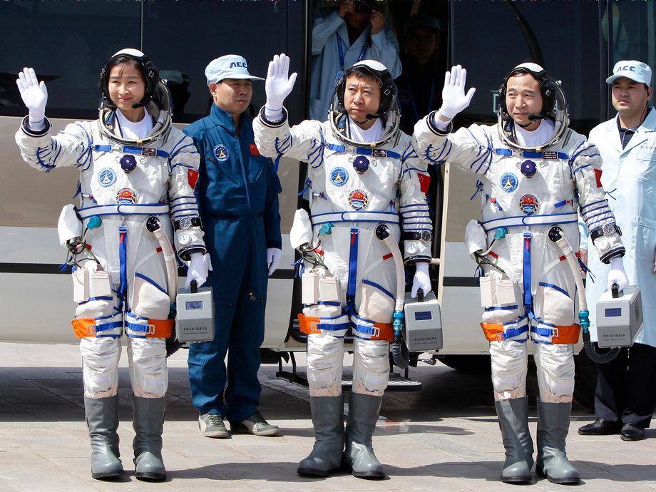 Chinese astronauts Jing Haipeng (R), Liu Wang (C) and Liu Yang, China's first female astronaut, wave as they leave for the launch tower during a departure ceremony at the Jiuquan Satellite Launch Center.