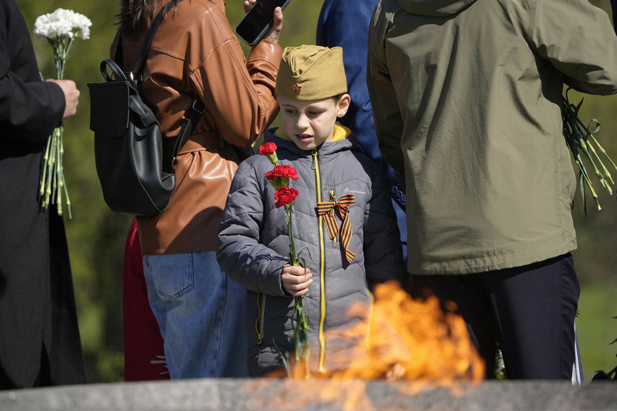 Chłopiec stoi obok znicza w przeddzień Dnia Zwycięstwa podczas ceremonii składania kwiatów i wieńców na Cmentarzu Piskarowskim, 8 maja 2023 r.