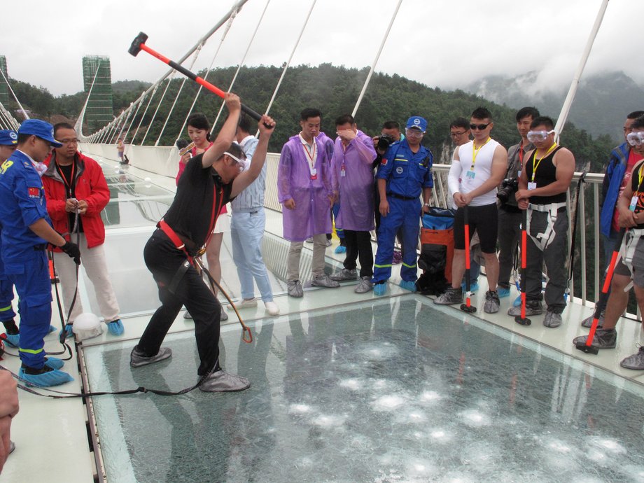 A man strikes the Zhangjiajie Grand Canyon Glass Bridge with a sledgehammer during a test ceremony on June 25, 2016