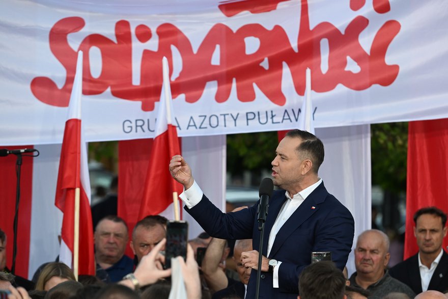 Karol Nawrocki na tle flagi Związku Zawodowego Solidarność