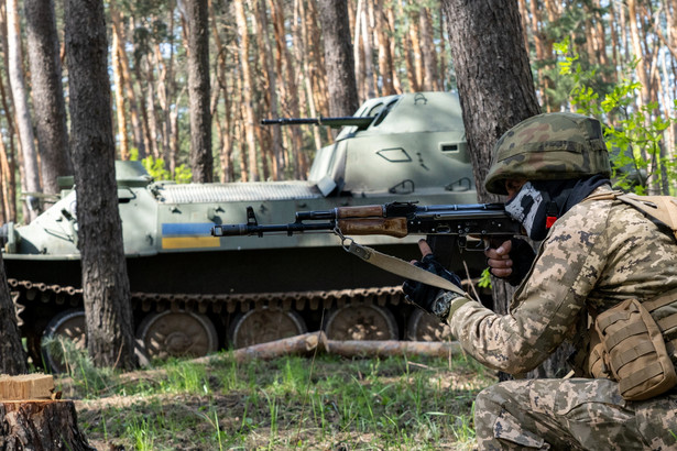Żołnierz Gwardii Narodowej Ukrainy i transporter opancerzony MT-LB na posterunku wojskowym na obrzeżach Charkowa