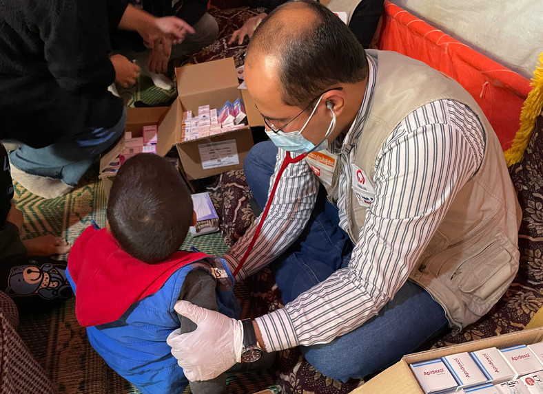 Lekarz bada dziecko w nieformalnym obozie uchodźców w Jordanii