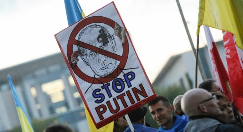 Protester demonstrate outsiude the chancellery in Berlin ahead of a meeting of leaders of Russia, Ukraine, France and Germany