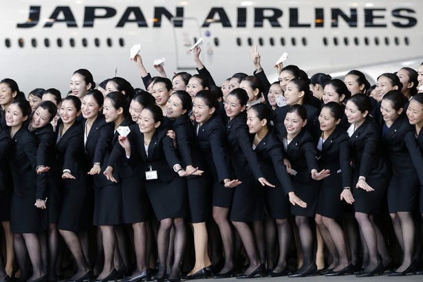 Nowo zatrudnione stewardessy linii lotniczych Japan Airlines pozują do zdjęcia na tle samolotu w barwach linii na lotnisku Haneda w Tokio