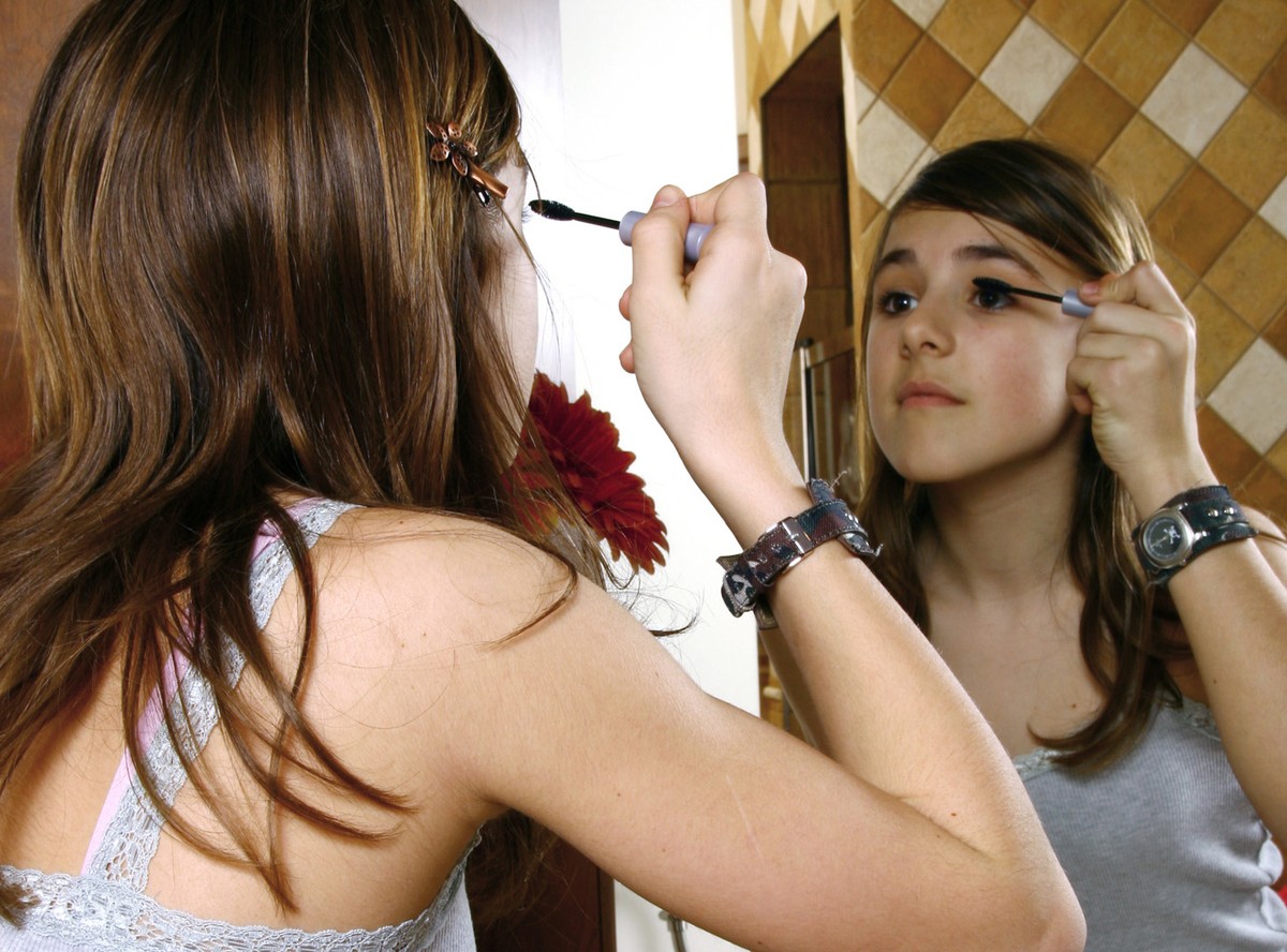 Nastolatka nakładająca makijaż przed lustrem