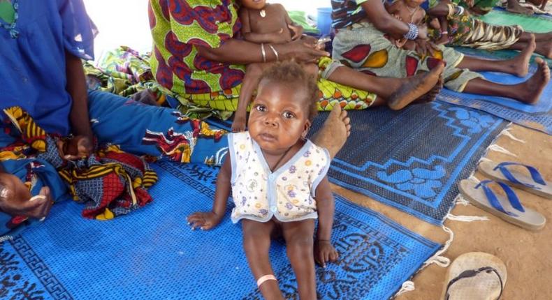 An infant suffering from malnutrition and malaria sits with others as they wait for treatment at an international NGO MSF (Doctors Without Boarders) outpost in Guidan-Roumdji 