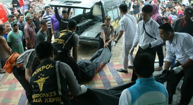 Indonesian police unload the bodies of victims after a boat carrying migrant workers capsized and sunk off Batam island