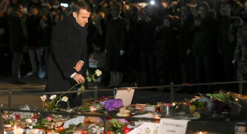 French President Emmanuel Macron lays a white rose at a monument near the Christmas market in Strasbourg, where four people where killed by a gunman this week