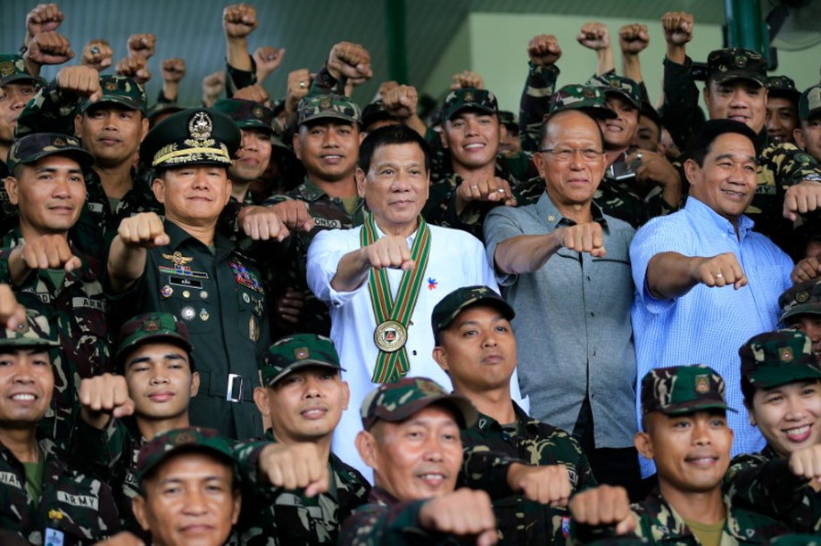 Philippine President Rodrigo Duterte, center, clenches his fist with members of the Philippine army at army headquarters in Taguig city, metro Manila, October 4, 2016.