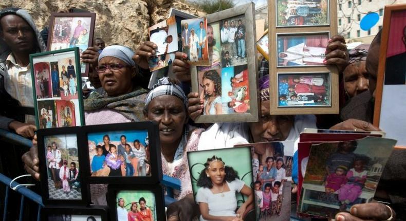 Ethiopian Israelis hold up photographs of relatives in a protest outside the premier's office in Jerusalem on March 20, 2016