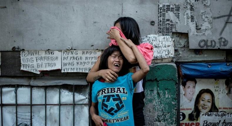 Two Filipinos mourn the death of a relative, a suspected drug dealer gunned down by unidentified assailants in Manila earlier in March as part of President Duterte's deadly drug war