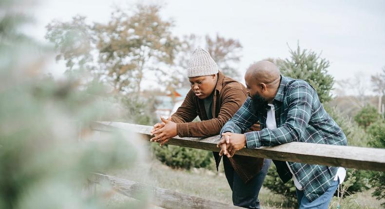 Black father conversing with teenager near fence on farmland [Image: Any Lane]