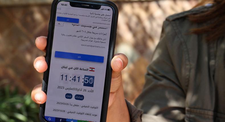 A woman in Beirut, Lebanon, holds a cellphone showing contradicting time zones on March 26, 2023, after Lebanon's government announced a decision to delay Daylight Savings Time.ANWAR AMRO/AFP via Getty Images