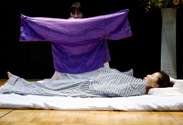 A funeral undertaker dresses a model during an encoffinment competition at Life Ending Industry EXPO