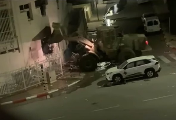 Buldożer niszczy budynek policji.