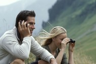 Man with cell phone and woman with binoculars